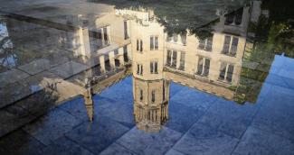 Color photo of University of Chicago Classics Building upside down, reflected in a puddle on the sidewalk