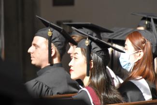 Graduating students in regalia glancing to the left