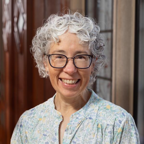 Portrait of Daisy Delogu standing in front of a wooden background inside UChicago