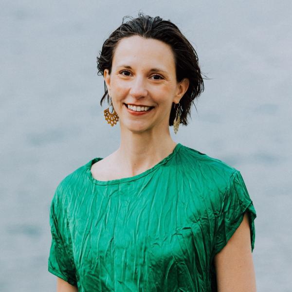 Portrait of Jennifer Iverson in a green dress in front of a light grey textured background