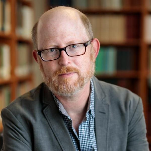 Portrait of Matthew Boyle sitting in front of a bookshelf in UChicago