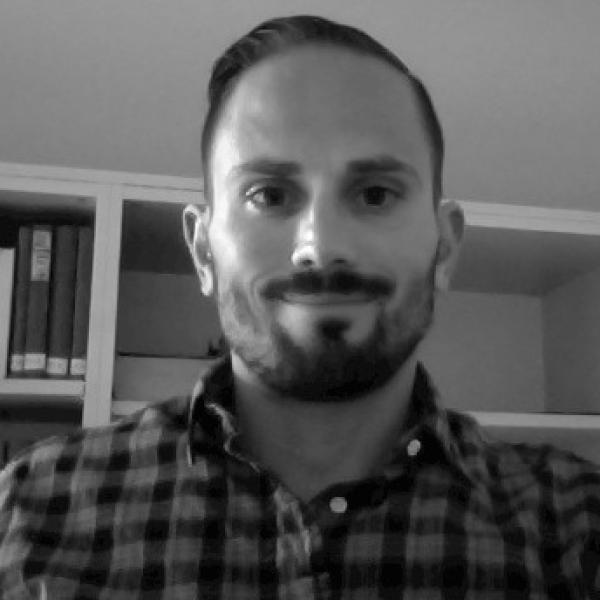 Black and white portrait of Christopher Simon in front of a bookcase