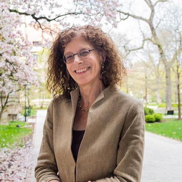 Portrait of Leora Auslander standing outside on UC campus in front of tree branches
