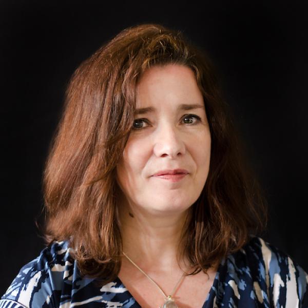 Portrait of Catriona MacLeod from the shoulders up in front of a black background