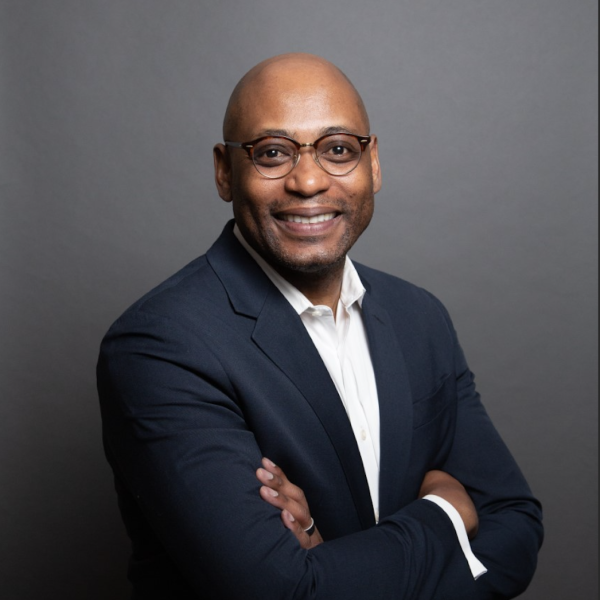 Portrait of Patrice Rankine from the waist up in front of a gray backdrop